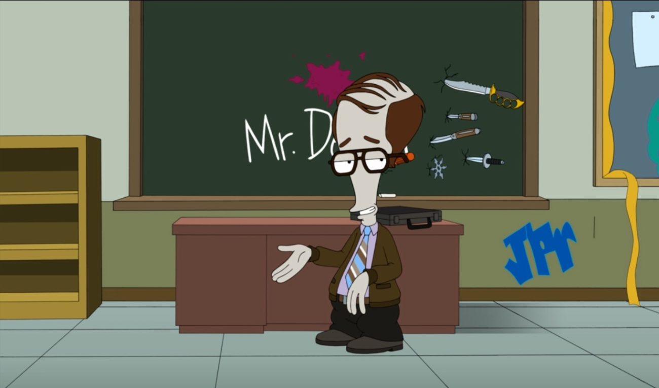 A bulbous-headed grey alien in a balding wig wears a brown jacket, blue striped tie, and lavender shirt; he stands in front of a graffiti-covered wall and chalkboard covered in knives (Roger Smith as Mr. Stan-Dan Deliver in American Dad!)