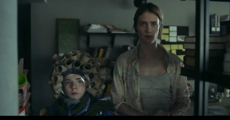 Young Kirsten (Matilda Lawler) and Adult Kirsten (Mackenzie Davis) stand in the shadows looking forward