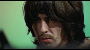 George Harrison, in close up, looks on