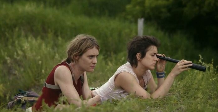 Kirsten (Mackenzie Davis) and Alex (Phillipine Velge) observe St. Deborah by the Water from a grassy knoll with a telescope in Station Eleven Episode 4