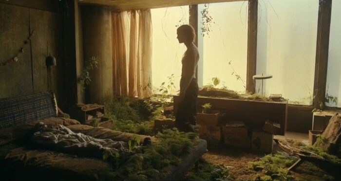 Kirsten (Mackenzie Davis) in Frank's overgrown room, looking down at his body