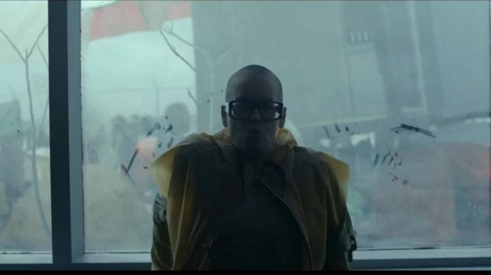 The Conductor (Lori Petty) tries to catch her breath in front of a large, foggy, window