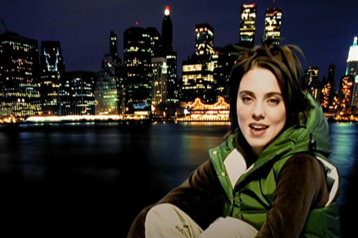 Melanie Chisolm singing at the start of the music video for 2 Become 1 with New York in the background.