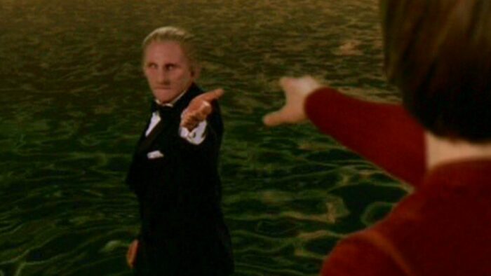 Tuxedo-clad Odo gestures goodbye to Kira, who reaches for him as he walks back into the sea that is the Great Link.