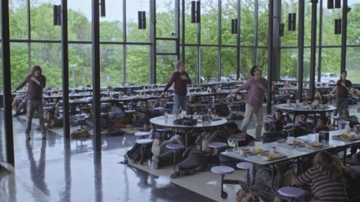 Jesse (Brendan Meyer), Steve (Patrick Gibson), French (Brandon Perea), and Buck (Ian Alexander) performing the movements in the school cafeteria while other students hide under the tables.