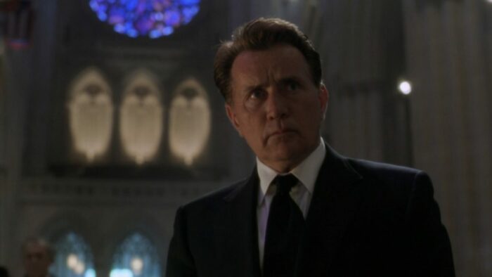 President Bartlet (Martin Sheen) stands beneath a stained glass window