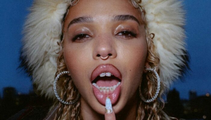 FKA Twigs slays on the cover of her Caprisongs mixtape, showing off her hoop earrings, septum piercing and fur hat against a twilight background