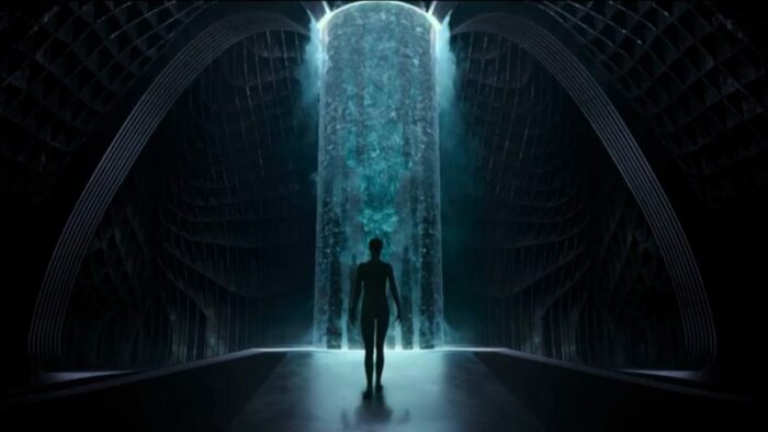 Mother silhouettted as she walks up to an enormous pillar of light in a large chamber
