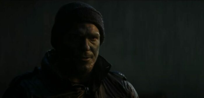 Jack Reacher in a black beanie and combat face paint outside in the rain 