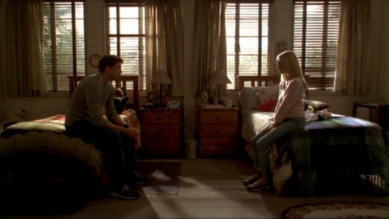 Buffy and Riley sitting on separate beds in Buffy's dorm in silence