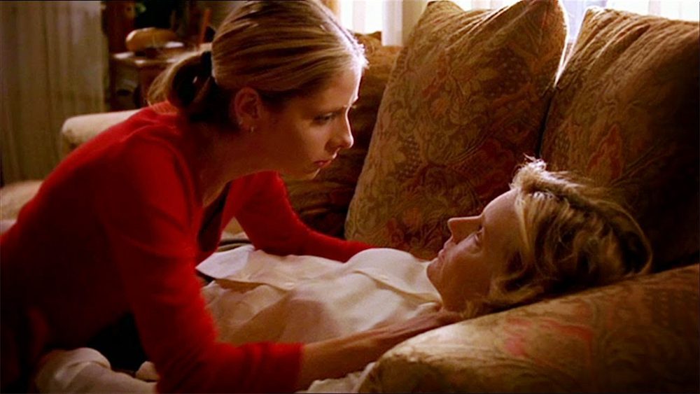 Traumatized and scared, Buffy Summers (Sarah Michelle Gellar) leans over the lifeless body of Joyce Summers (Kristine Sutherland) collapsed on the couch.