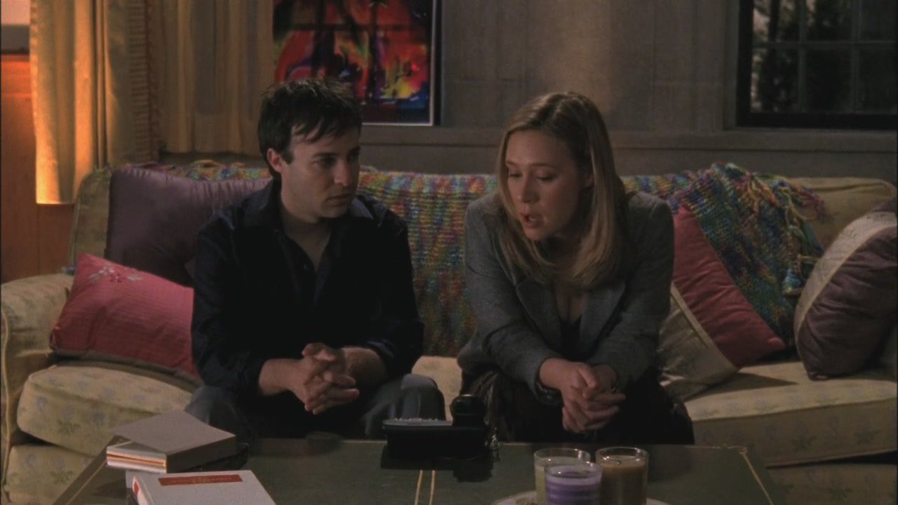 Doyle (Danny Strong) and Paris (Liza Weil) sit on the couch and talk to someone on the speaker phone.