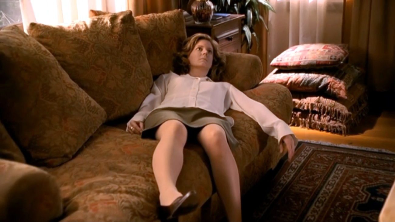 The limp, lifeless body of Joyce Summers (Kristine Sutherland) lies arms splayed open on a light brown couch.