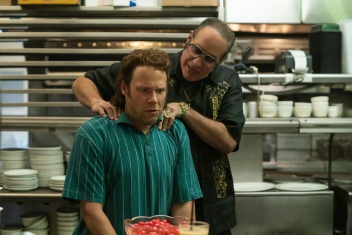 Rand (Seth Rogen) sits uncomfortably while Butchie (Andrew Dice Clay) massages his shoulders. 