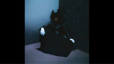 A figure in a black robe sits in the corner, wearing white gloves, on the cover of Bakar's Nobody's Home