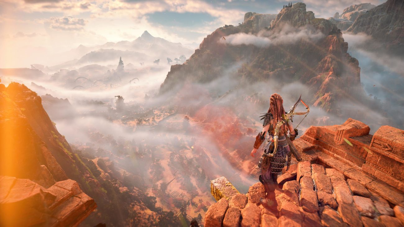 Aloy looks out across a vast landscape from atop a cliff