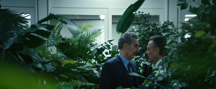 Burt and Irving stand face to face in a room full of plants