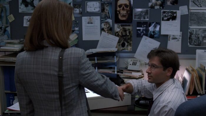 Mulder and Scully shake hands, meeting for the first time in the X-Files office