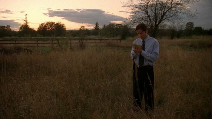Agent Mulder stands alone in a field staring sadly at a photograph