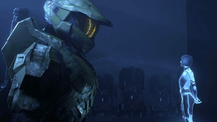 Master Chief and The Weapon face each other in a large, blue Forerunner room.