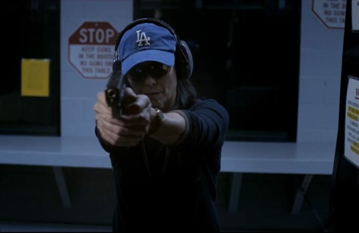 Honey Chandler in a blue LA dodgers hat aims and shoots a 9mm pistol at a shooting range