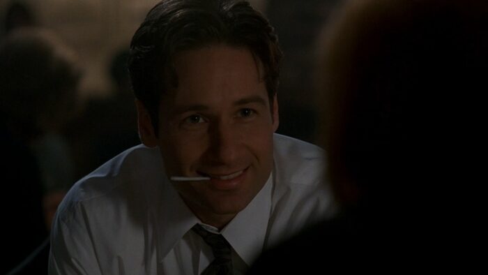 Mulder smiles happily at Scully, in a restaurant celebrating her birthday