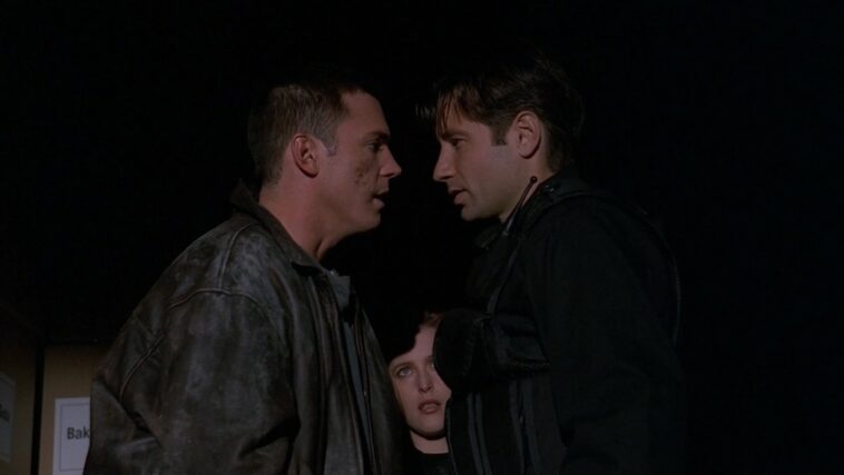 Mulder and Krycek stand nose-to-nose as Scully looks on
