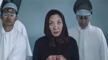 Michelle Yeoh in black with figures in white to each side of her in Everything Everywhere All At Once