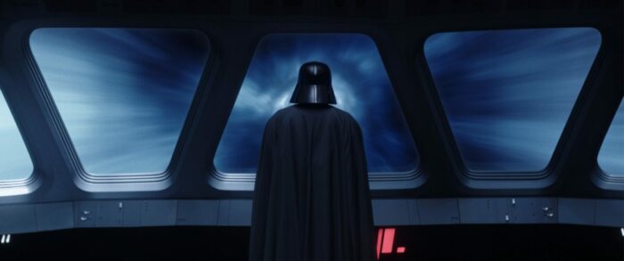 Vader stands, back turned, looking out a window during hyperdrive