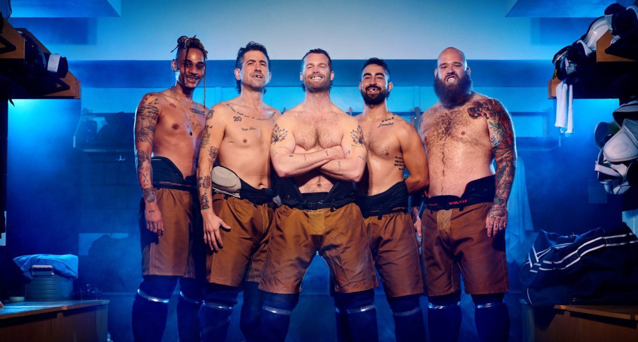 Five shirtless men, all missing teeth, in a hockey locker room