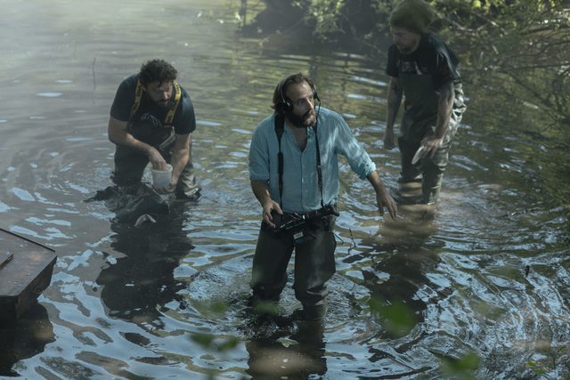 Rene Vidal (Vincent Macaigne) directs a scene in a pond as two assistants watch.