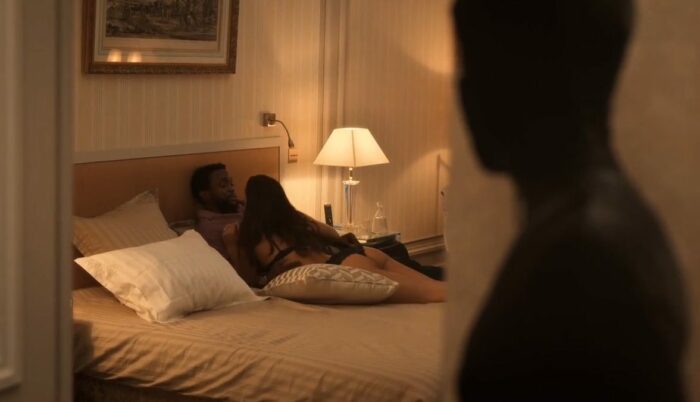 Mira, wearing the Irma Vep catsuit, watches Herman and Laurie in their hotel bedroom. Photo: HBO.