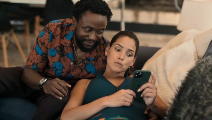 Herman (Byron Bowers) and Laurie (Adria Arjona) look at a message on a cell phone.