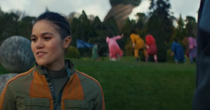 Bella stands in front of a group of Mooners who dance in the background in the Moonhaven pilot