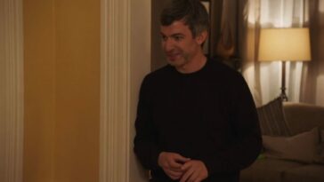 Nathan has a bit of a smirk on his face as he stands in Angela's house