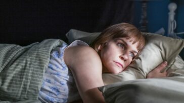 Kim Wexler lays on her side alone in bed