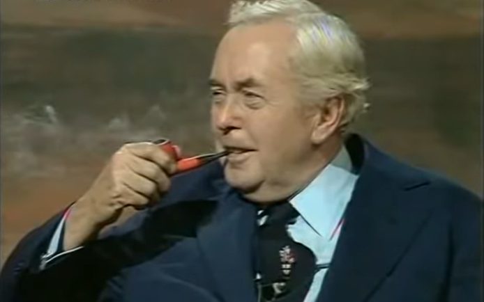 Wilson, dressed in a suit, smokes his famous pipe.