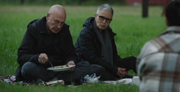 Nathan's parents sit cross-legged in the grass