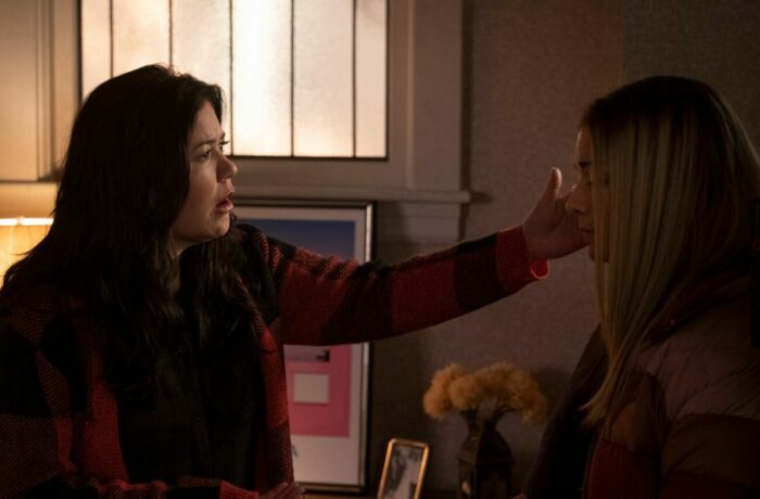 Patty puts a hand to Allison's head as they stand in a living room