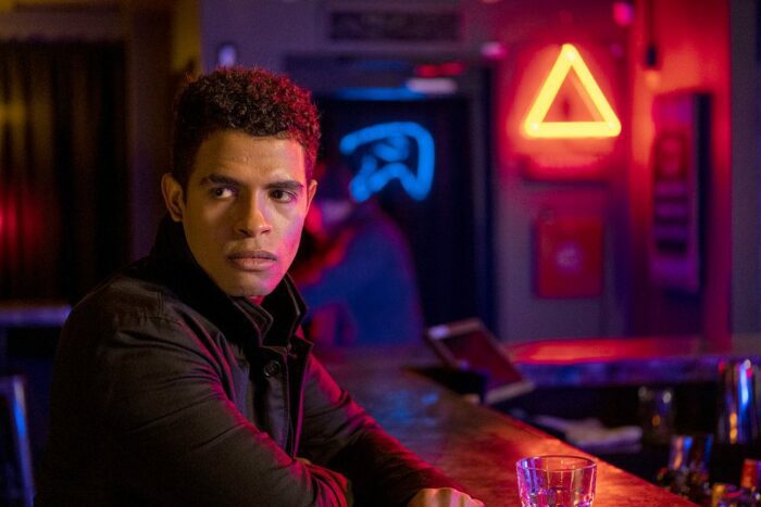 Pictured: Mandela Van Peebles as Maurice standing at the bar where he's interrupted by Angela's goons
