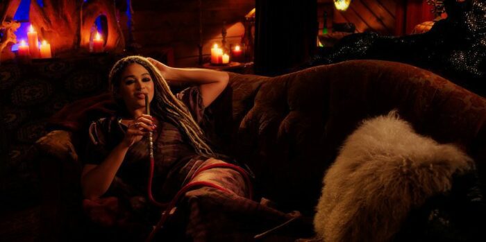 Savannah Basley as Angela lounging on the couch in her lair drinking blood through a straw