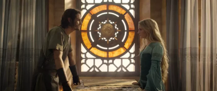 Galadriel and Halbrand give each other a smoldering look in front of a stained glass window