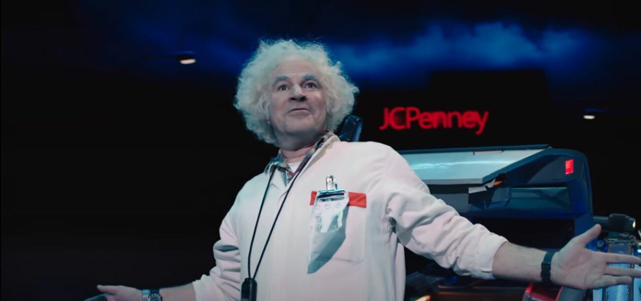 Doc Brown wearing white, with arms splayed, in front of a JCPenny sign, in the trailer for Back to the Future: The Musical