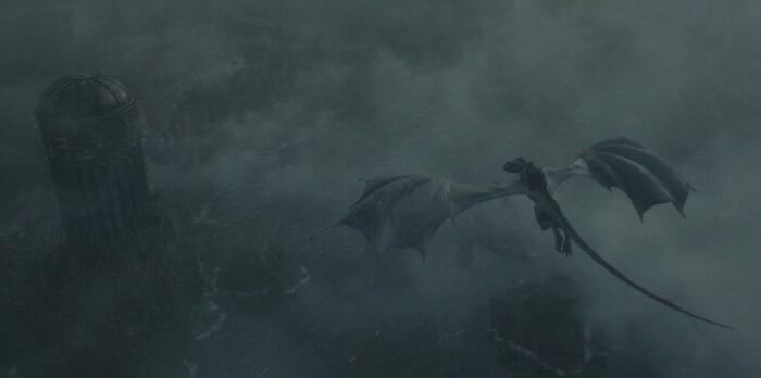 A boy on dragonback flying through a storm towards a castle