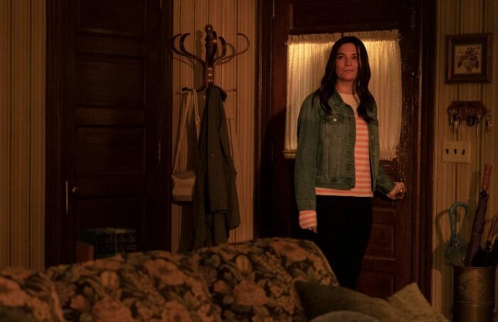 Allison, with dark hair, stands framed by the door as she prepares to leave the house, smirking in Kevin Can F**k Himself S2E8