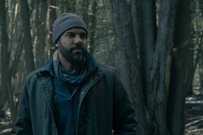 Luke stands in the woods wearing a knit cap