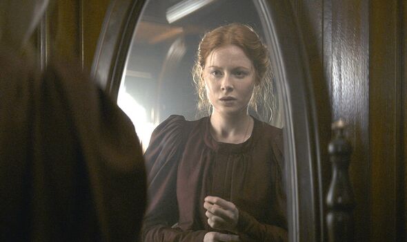 Maura looks at herself in the mirror in 1899