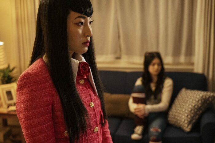 Christin Park as Nikki at Claire's apartment with Claire on the couch in the background
