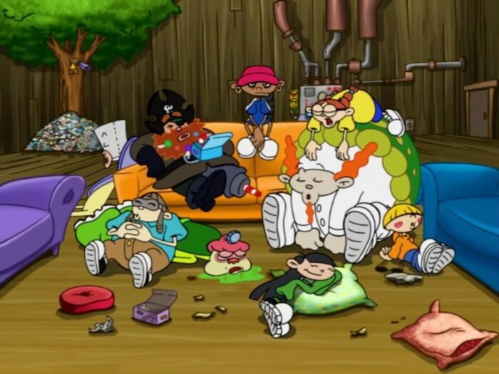 Numbuh Five, looking exhausted and miffed, siting on the back of an orange couch adorned with the sleeping forms of her teammates alongside a couple of villains she knocked out.
