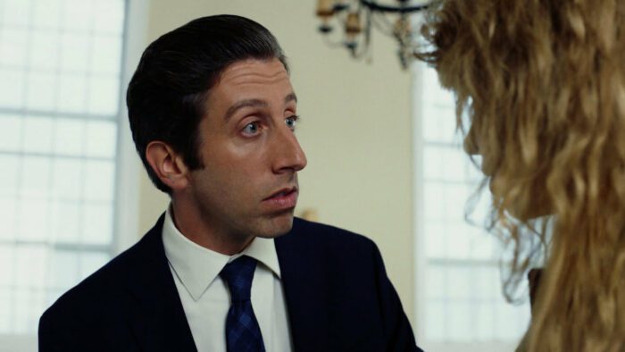 Luca (Simon Helberg) looks inquisitively at Charlie while standing in front of a white wall with bright windows